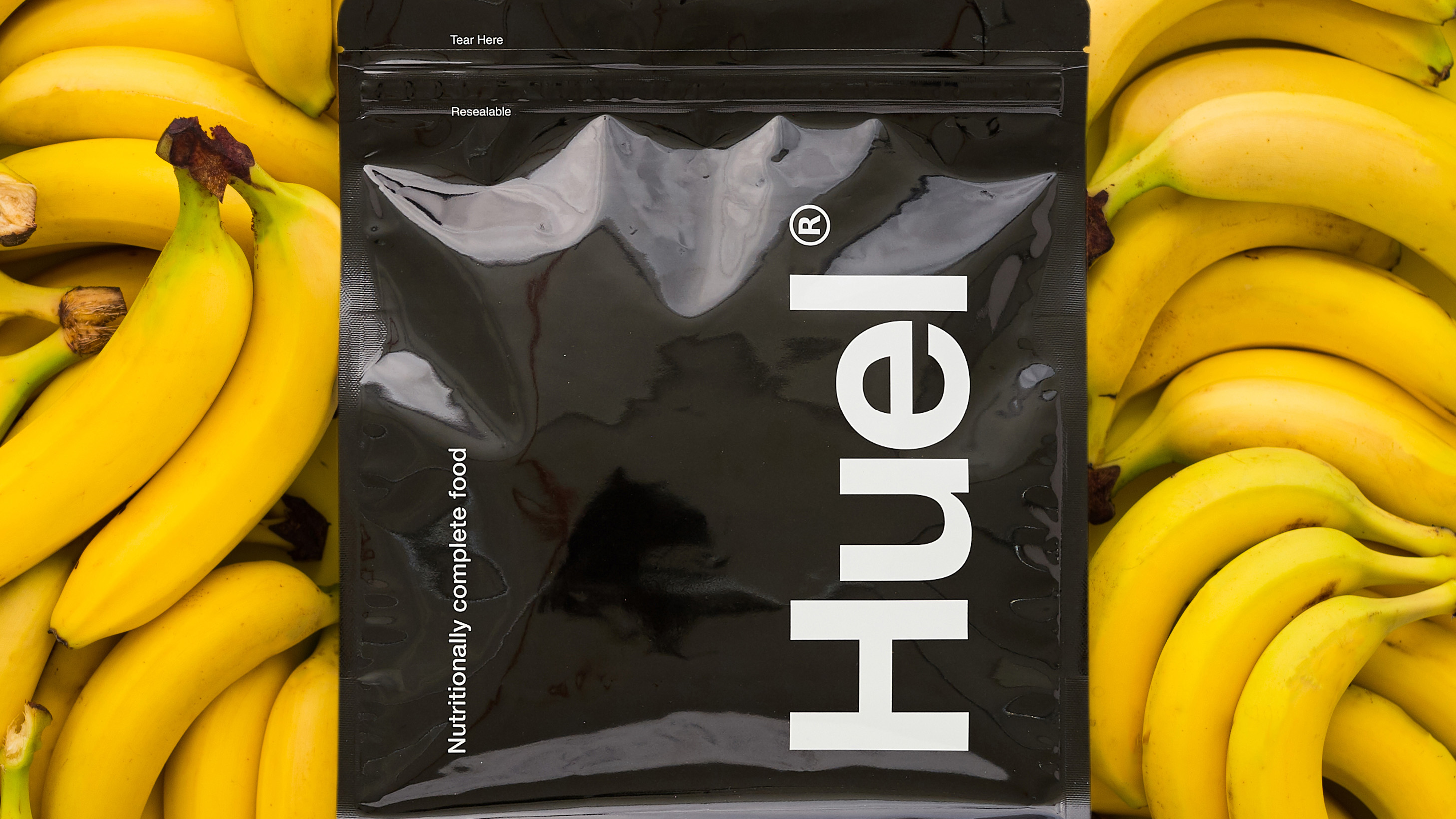 Huel Black Edition против Bulk 1 Complete Food Shake: пакет Huel Black Edition, помещенный поверх кучи бананов