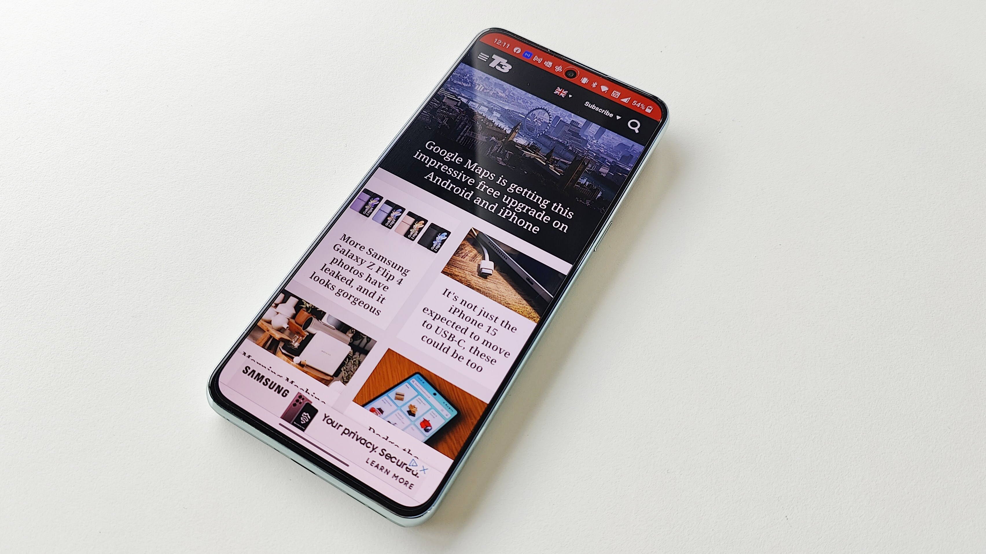 Веб-сайт OnePlus 10T T3 открыт на экране телефона, лежащего на белом столе