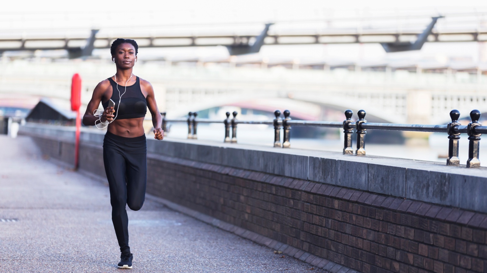 Как пробежать 5 км быстрее: на этом снимке спортсменка бегает по берегу Темзы рано утром, слушая музыку на своем смартфоне или плеере.