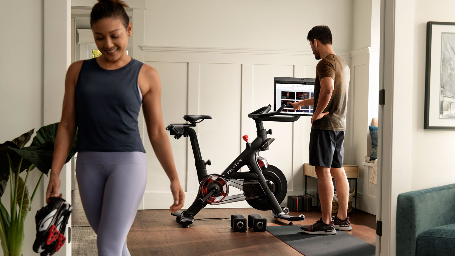 Мужчина взаимодействует с дисплеем Peloton Bike+ в комнате.