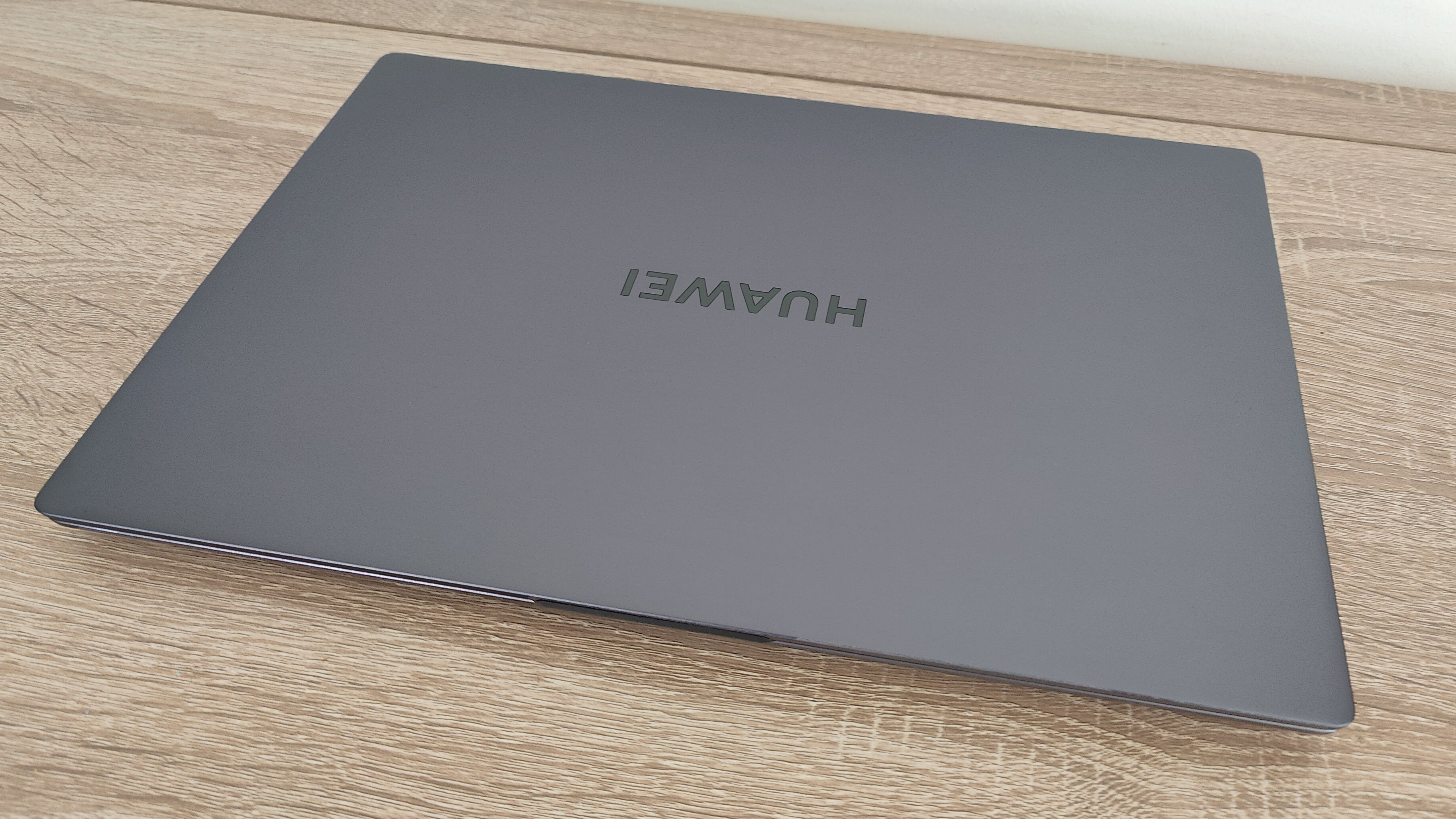 Обзор Huawei Matebook D 16: серый ноутбук, закрытый на столе белой стеной