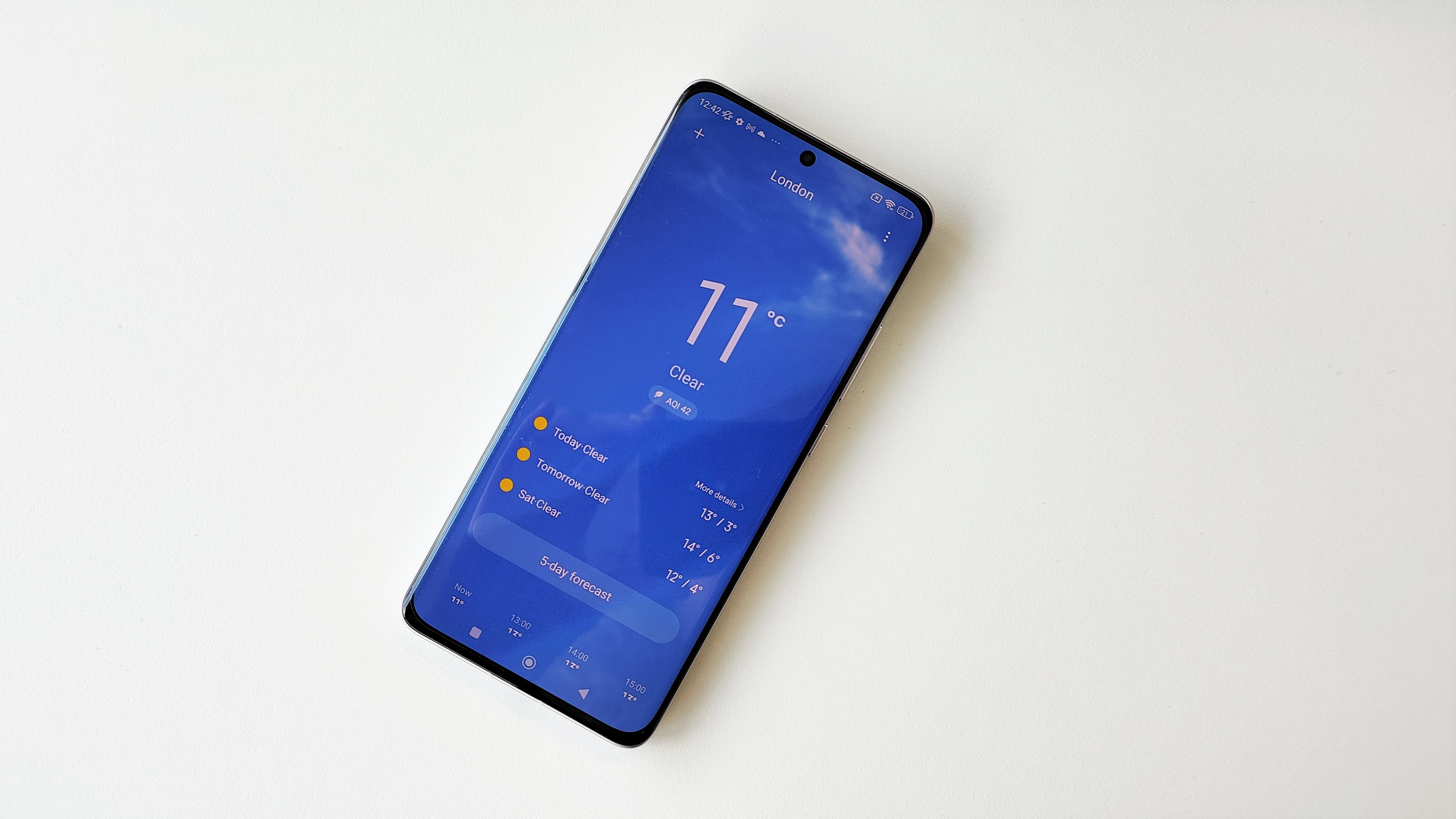 Обзор Xiaomi 12: приложение погоды, открытое на телефоне, размещено на белом столе