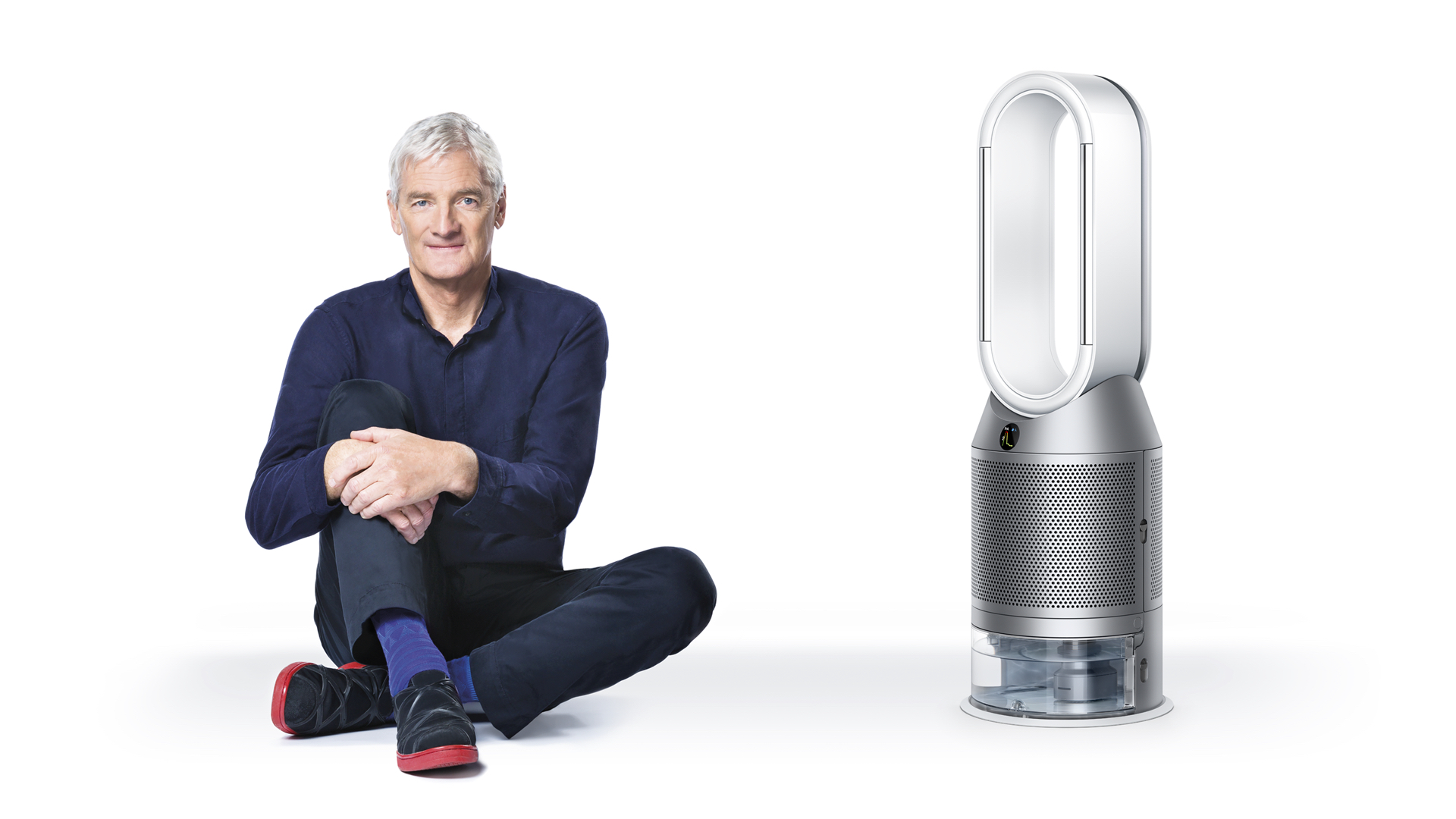 Сэр Джеймс Дайсон сидел рядом с очистителем Dyson Purifier Humidify+Cool.