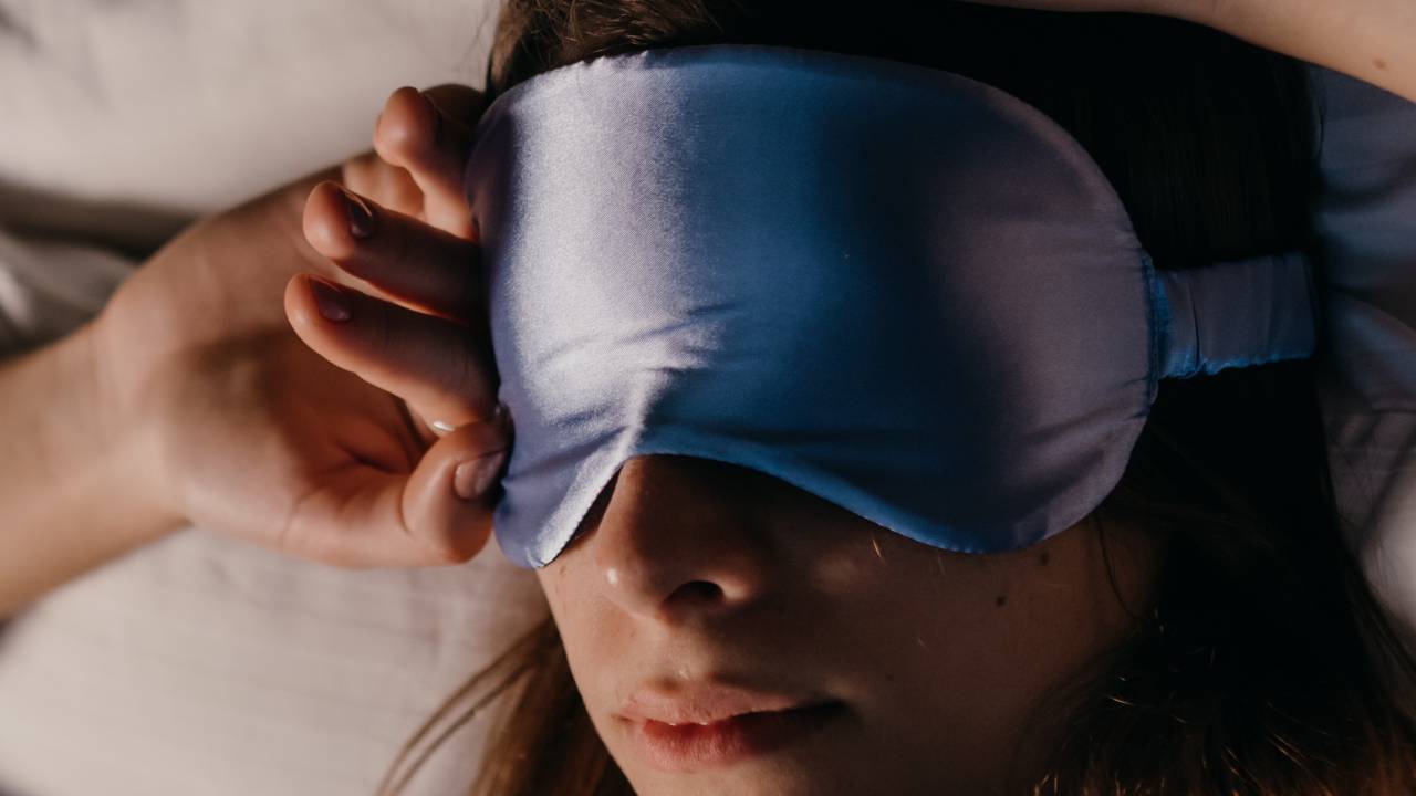 Женщина в синей шелковой маске для сна